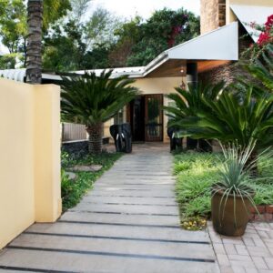 Entrance of Riverbank Lodge in Upington with cycads, palms and bougainvillea