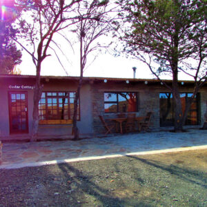 Фасад Cedar Cottage с каменными стенами и верандой в Rogge Cloof близ Сатерленда