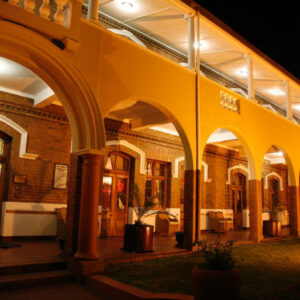 Lit brick arcade and veranda of the Victorian Kimberley Club building at night